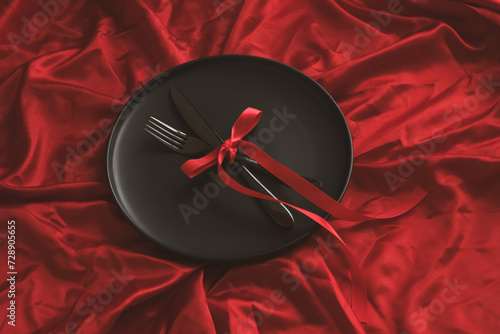 There is a plate with cutlery on a red background. Holiday concept
