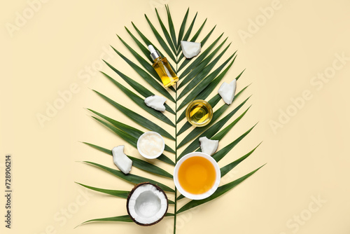 Bowls and bottle of coconut cosmetic oil with plant leaf on beige background