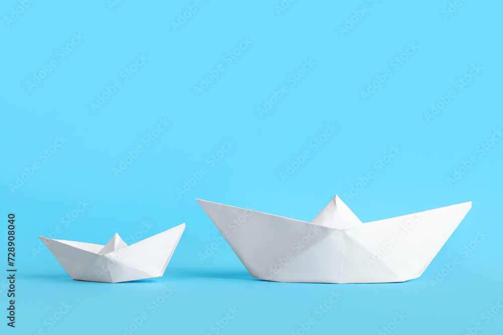 White origami boats on blue background White origami boats on blue background