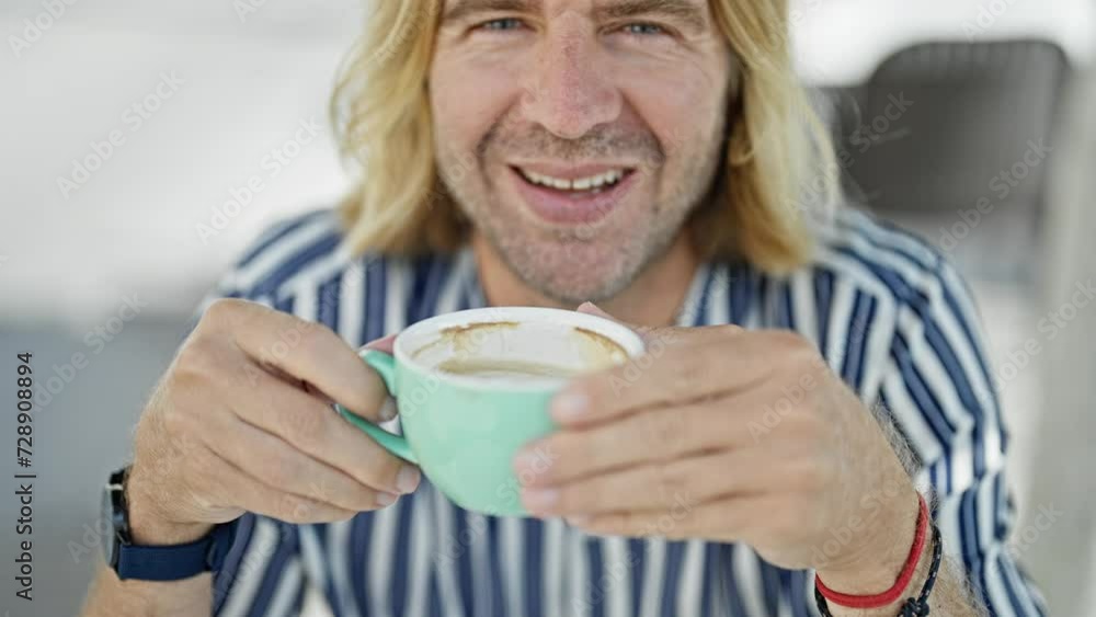 A smiling long-haired man enjoying coffee outside A smiling long-haired man enjoying coffee outside
