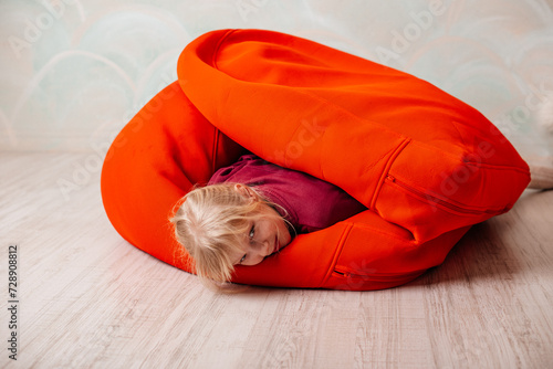Girl having fun and fooling around with red bean bag chairs, floor pillows