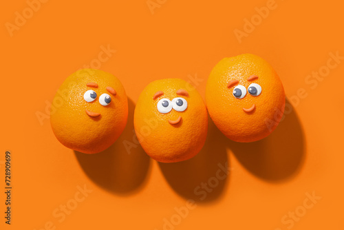 Orange fruits with funny faces on color background