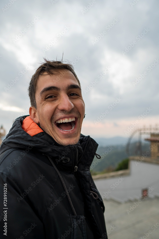 Young brunet man in jacket laughing out loud. Vertical
