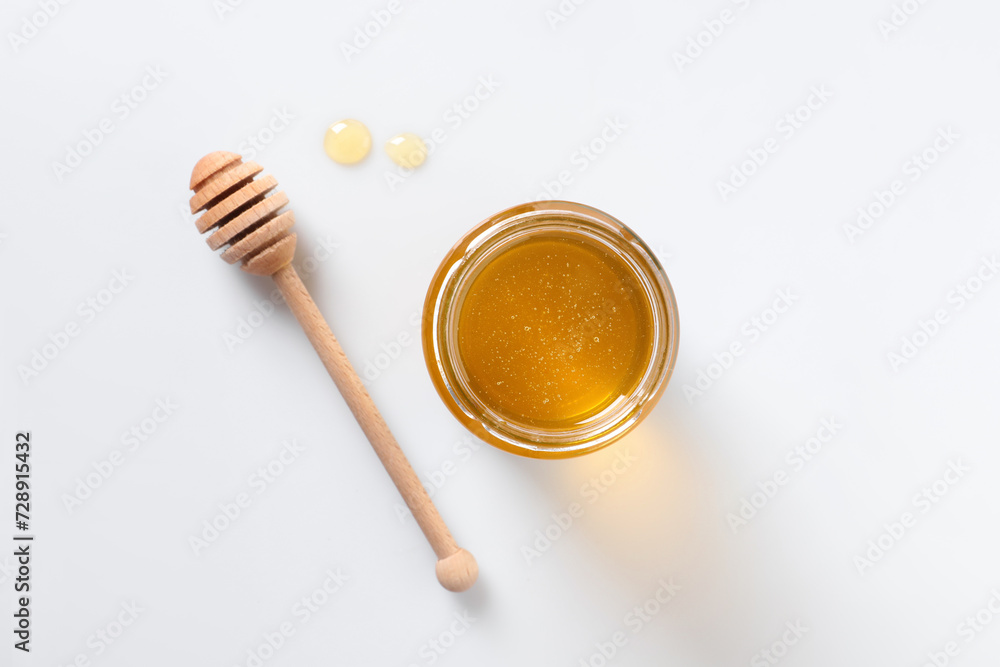 Tasty honey in glass jar and dipper on white background, top view Tasty honey in glass jar and dipper on white background, top view