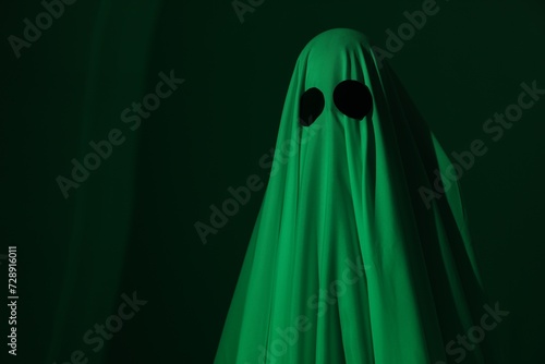 Creepy ghost. Woman covered with sheet in green light, space for text