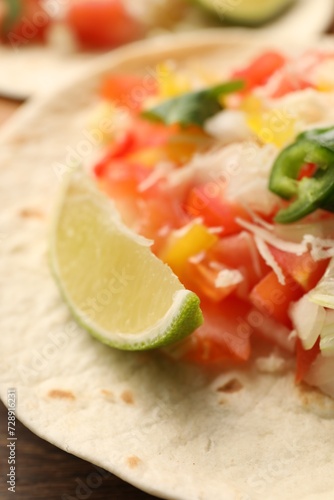 Delicious taco with vegetables and lime on table, closeup