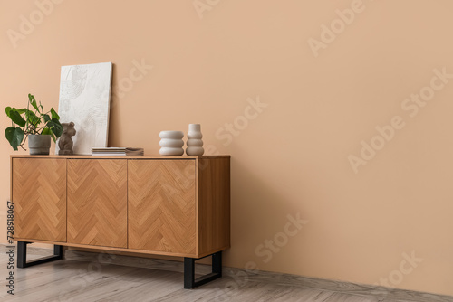 Schilderij op canvas Wooden sideboard with houseplant, magazines and decor near beige wall