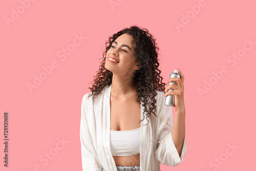 Beautiful African-American woman with hair spray on pink background photo