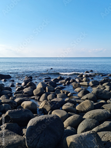 This is a Jeju beach with blue skies and basalt rocks.