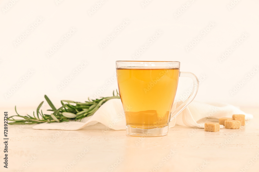 Glass cup of hot rosemary tea and sugar on beige background Glass cup of hot rosemary tea and sugar on beige background
