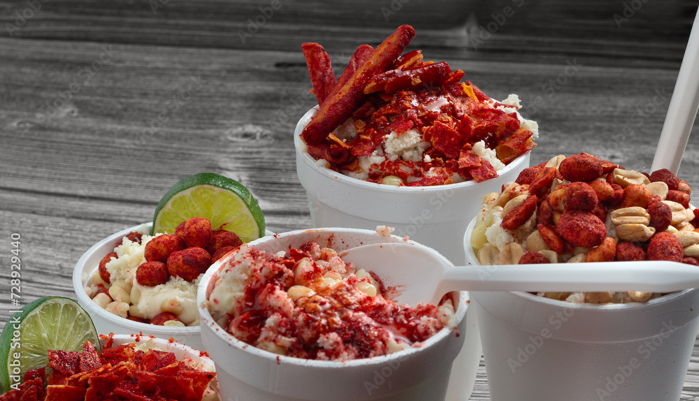 group of Mexican snacks, several corns in cups, prepared with chili, peanuts, chips, chamoy sauce, delicious group of Mexican snacks, several corns in cups, prepared with chili, peanuts, chips, chamoy sauce, delicious