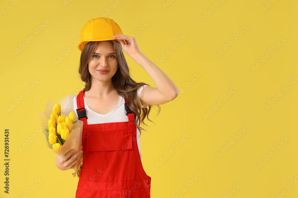 Female mechanic with bouquet of tulips on yellow background. International Women's Day celebration Female mechanic with bouquet of tulips on yellow background. International Women's Day celebration