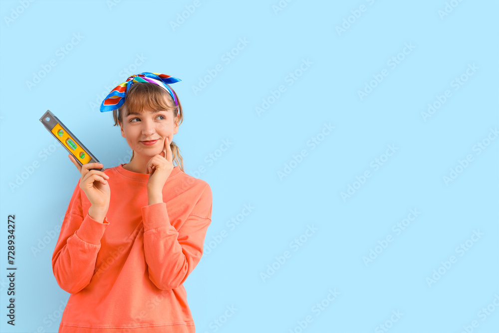 Thoughtful young woman with spirit level on blue background. Repair concept Thoughtful young woman with spirit level on blue background. Repair concept