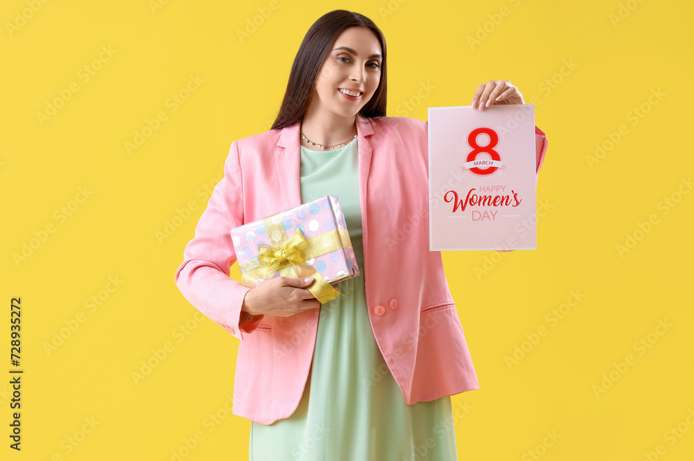 Young woman with card for International Women's Day and gift on yellow background Young woman with card for International Women's Day and gift on yellow background
