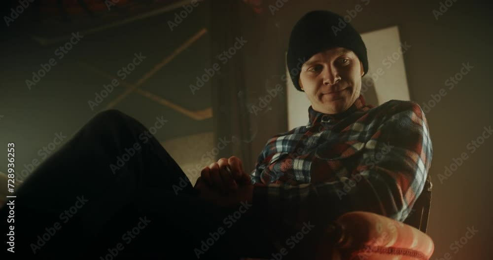 Lumberjack in his small room, holding smoking cigarette and nodding his head back and forth to music Lumberjack in his small room, holding smoking cigarette and nodding his head back and forth to music