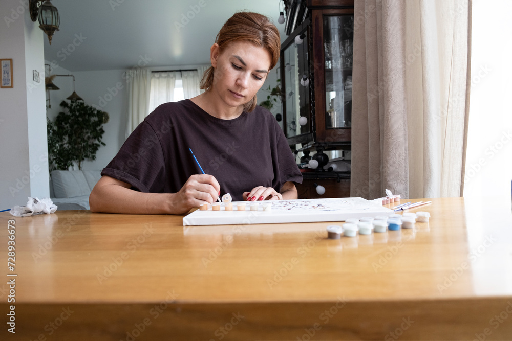 Adult woman draws a picture by numbers. Middle age person drawing at home Adult woman draws a picture by numbers. Middle age person drawing at home