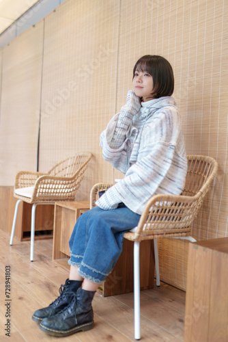 香港の寒い冬に街なかの休憩所で休憩する20代の中国人女性 A Chinese woman in her 20s taking a break at a rest area in the city in the cold winter in Hong Kong