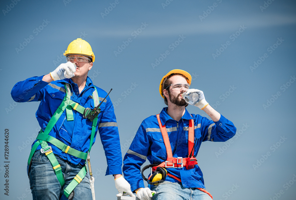 Male technician holding solar panels on factory roof An engineer in a helmet takes a drink break before installing an outdoor solar panel system. solar cell storage Male technician holding solar panels on factory roof An engineer in a helmet takes a drink break before installing an outdoor solar panel system. solar cell storage