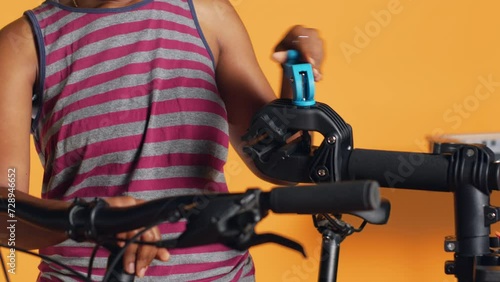 Serviceman setting up bike repair stand before starting work on defective wheels, studio background. Professional preparing bicycle workstand before inspection, close up shot photo