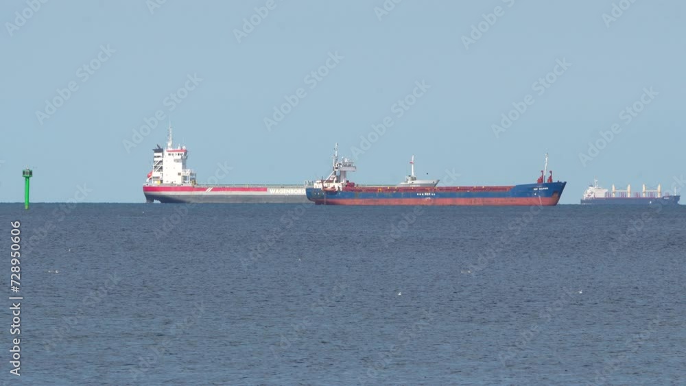 A red and white cargo ship sails on a calm blue sea under a clear sky, possibly a tanker, with a navigation buoy visible, symbolizing maritime transport and global commerce A red and white cargo ship sails on a calm blue sea under a clear sky, possibly a tanker, with a navigation buoy visible, symbolizing maritime transport and global commerce