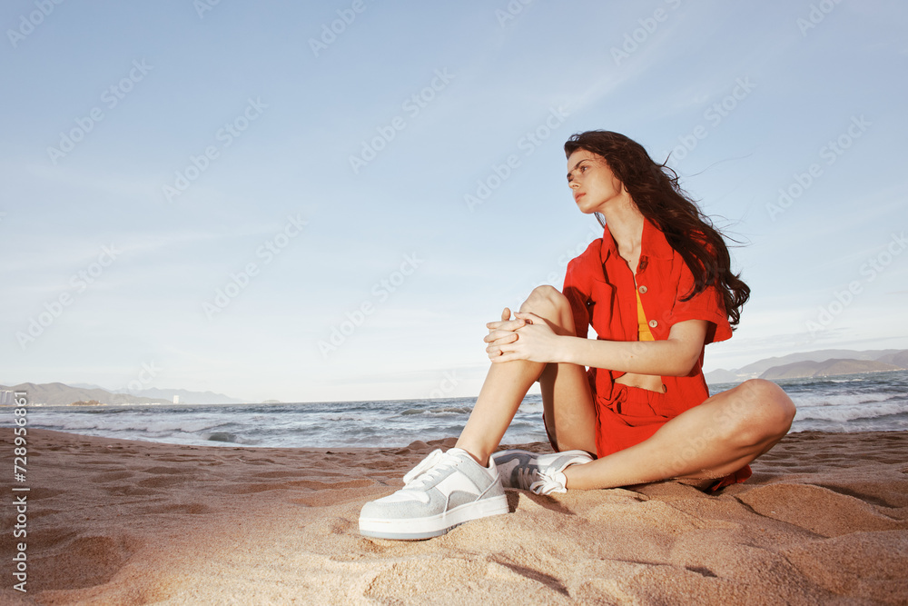 Smiling Woman Sitting on Sandy Beach, Enjoying Trendy Fashion Outfit in Wide Angle Summer Portrait