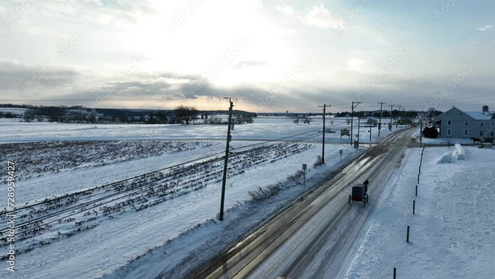 Rural USA during winter. Snow with Amish horse and buggy. Aerial rising shot during sunrise. Rural USA during winter. Snow with Amish horse and buggy. Aerial rising shot during sunrise.