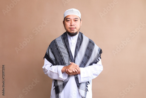 Portrait of bearded Asian muslim man  in white robe and cap photo