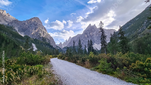 Scenic hiking trail along alpine meadow in panoramic valley Fischleintal near Moos. Panoramic view of majestic mountain ridges of Sexten Dolomites in Italian Alps. Wanderlust. Tranquil peaceful scene