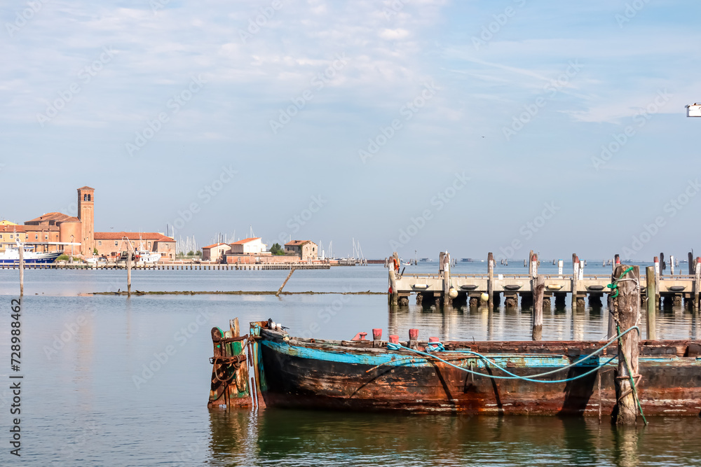 Old fishing boat in Sottomarina, Veneto, Northern Italy, Europe. Panoramic view on idyllic harbor of tourist town Chioggia. Wooden stilts in the Venetian Lagoon, Adriatic Mediterranean Sea in summer
