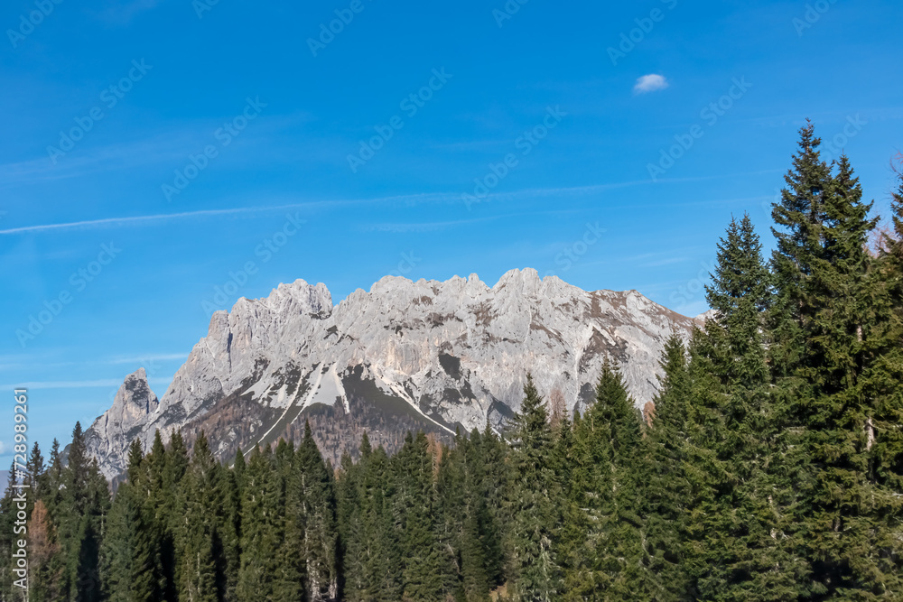 Scenic view of majestic mountains of Carnic Alps in Sauris di Sopra, Friuli Venezia Giulia, Italy. Serene tranquil atmosphere in Italian Alps. Lush green forest in on sunny blue sky day. Wanderlust