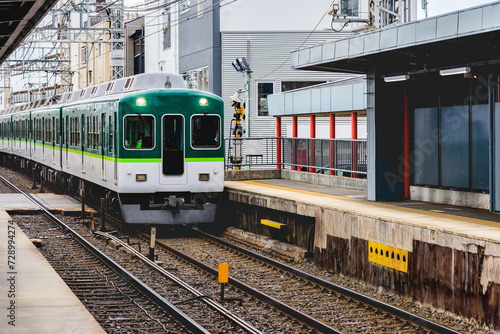 Local train, railcar arrive to railway station platform in rainy day in Japan.