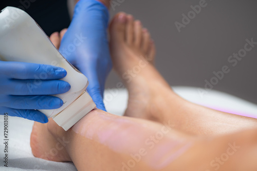Skilled beautician removes unwanted hair from a female leg using wax strips, unveiling a smooth and flawless result