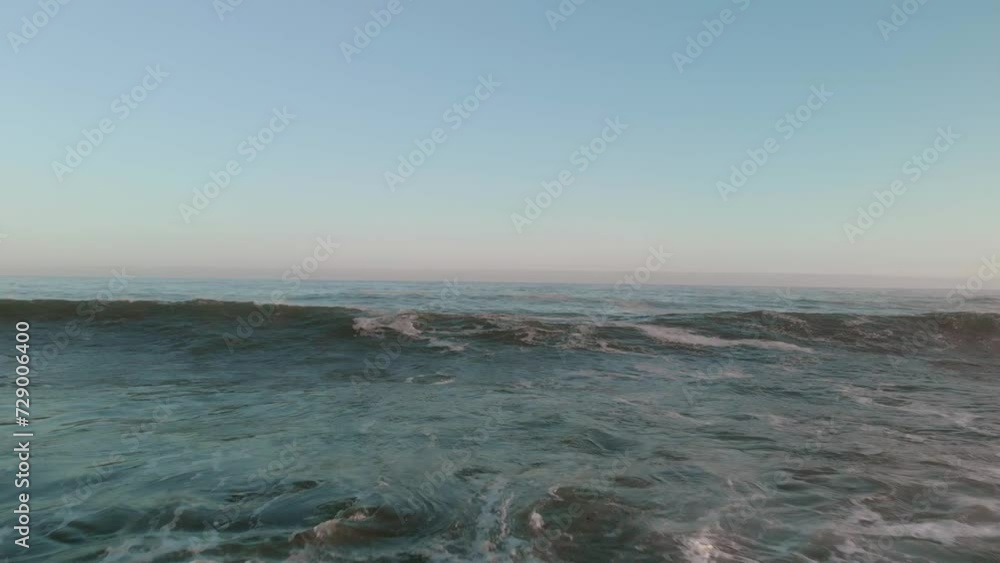 Drone flying low over open waters with bamboo floating on the surface as swells and waves come in and break Drone flying low over open waters with bamboo floating on the surface as swells and waves come in and break