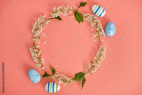 Easter eggs and cherry branches in the shape of a circle on a pink background. Copy space. Easter background, top view