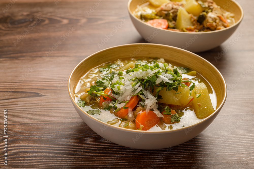 Chicken soup with vegetables in a deep bowl on a wooden table. Chicken soup with vegetables in a deep bowl on a wooden table.