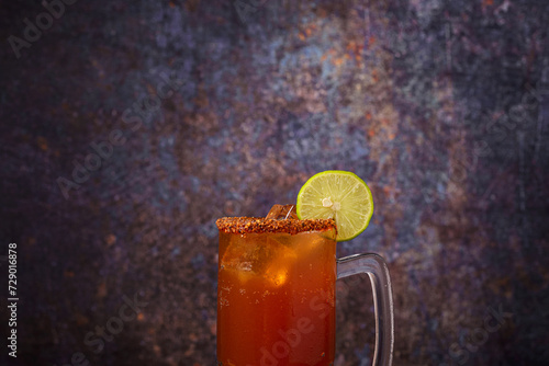 Michelada, typical mexican cocktail on a wooden table. Cocktail based on beer. photo