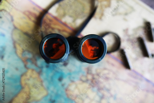 Binoculars and reflection in lenses. Map and shells background.