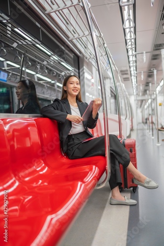 Young asian businesswoman traveling to airport on skytrain checking information using her digital tablet © asean studio