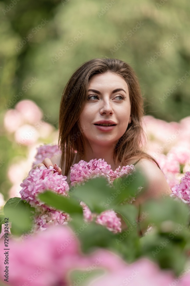 Hydrangeas Happy woman in pink dress amid hydrangeas. Large pink hydrangea caps surround woman. Sunny outdoor setting. Showcasing happy woman amid hydrangea bloom. Hydrangeas Happy woman in pink dress amid hydrangeas. Large pink hydrangea caps surround woman. Sunny outdoor setting. Showcasing happy woman amid hydrangea bloom.