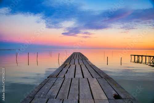 Fototapeta Naklejka Na Ścianę i Meble -  Scenic view of a wooden pier over a lake at sunset