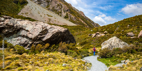 hiker girl walking alongside hooker valley track toward hooker lake and mt cook, famous walk in canterbury, new zealand south island