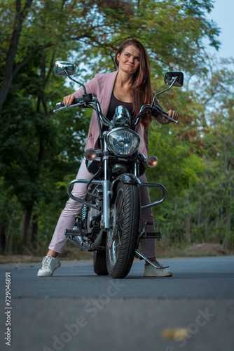 Young Woman In A Suit Posing On A Motorcycle In A Forest