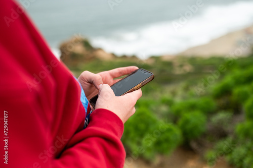 Person using smartphone with sea view photo