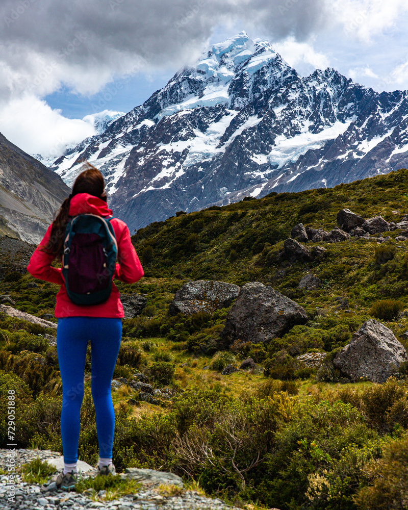 Fototapeta premium hiker girl walking alongside hooker valley track toward hooker lake and mt cook, famous walk in canterbury, new zealand south island