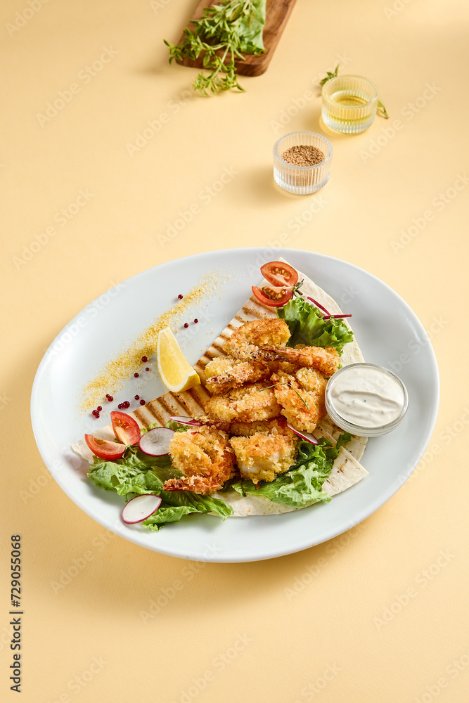 Tempura shrimp with tartar sauce on a bed of lettuce, presented on a white plate with lemon and tomato accents, against a soft yellow backdrop