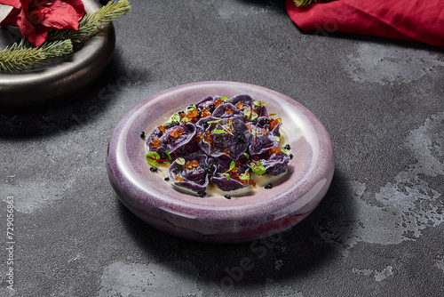 Black dumplings or ravioli with seafood and caviar in an elegant style, aesthetically pleasing winter menu