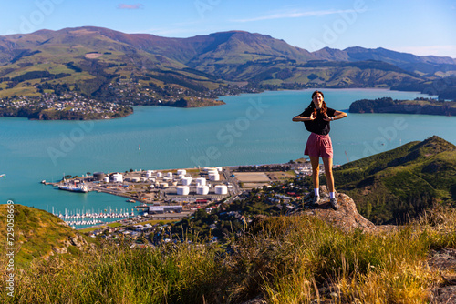 pretty hiker girl enjoying the panorama of lyttelton after finishing the hike on the bridle path from christchurch to lyttelton; beautiful view from gondola summit station, canterbury, new zealand  photo