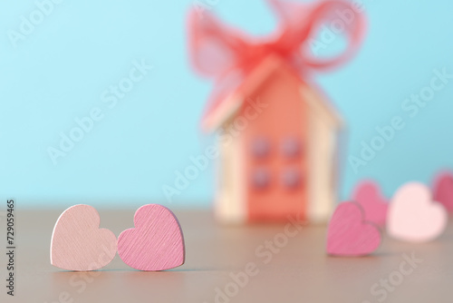 Decorative hearts over defocused background with house model with red bow