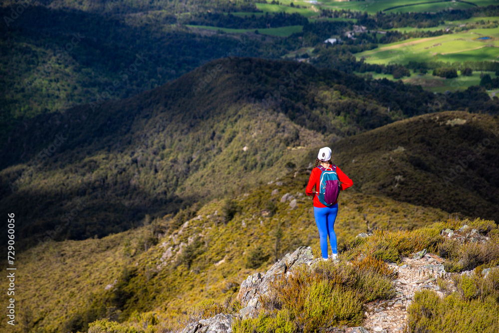 hiker girl walking down the steep trail from the top of mount somers in canterbury, new zealand south island