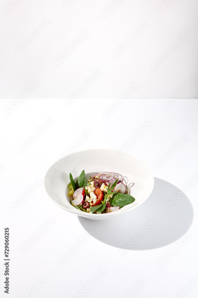 Greek salad isolated on a white background with crisp vegetables and feta cheese Greek salad isolated on a white background with crisp vegetables and feta cheese